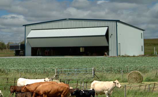 Farm building equipped with a bifold door, housing farm equipment