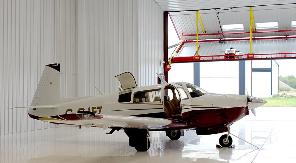 Plane parked inside of hangar that utilizes Schweiss' automatic latching system