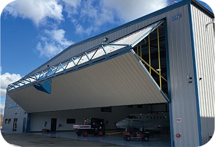 Exterior view of Schweiss Lift Straps on bifold door of jet hangar