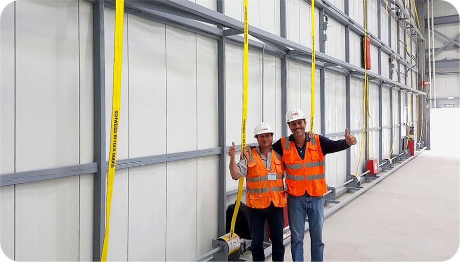 Happy customers in front of their Schweiss bifold door with liftstraps