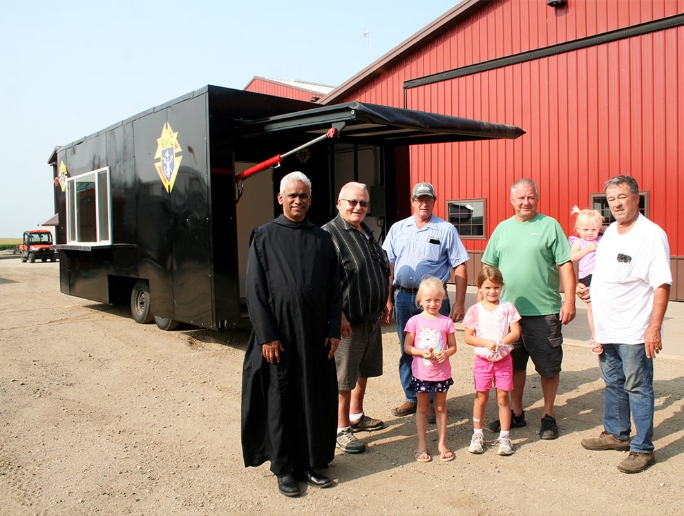 Mike Schweiss, his grandkids, a member of the Knights of Columbus and others posed in front of the Knights of Columbus food wagon