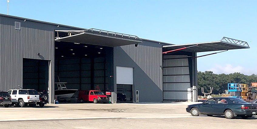 A bifold door and a hydraulic door installed side by side on building shown open