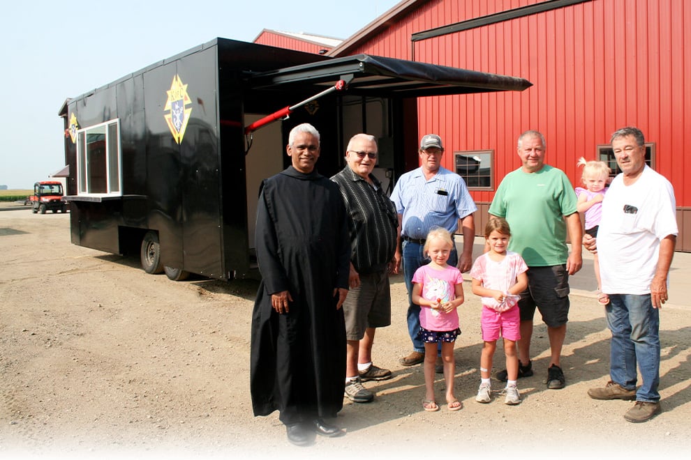 Mike Schweiss, his grandkids, a member of the Knights of Columbus and others posed in front of the Knights of Columbus food wagon