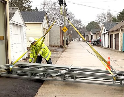 Schweiss bifold shipping container door being unloaded from trailer to put on smaller semi trailer to fit down Jeffrey's small alley