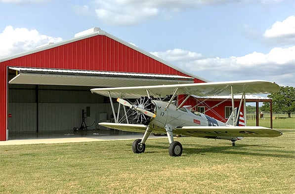 Schweiss bifold hangar door opens up to grass runway when flying PT-17 Stearman