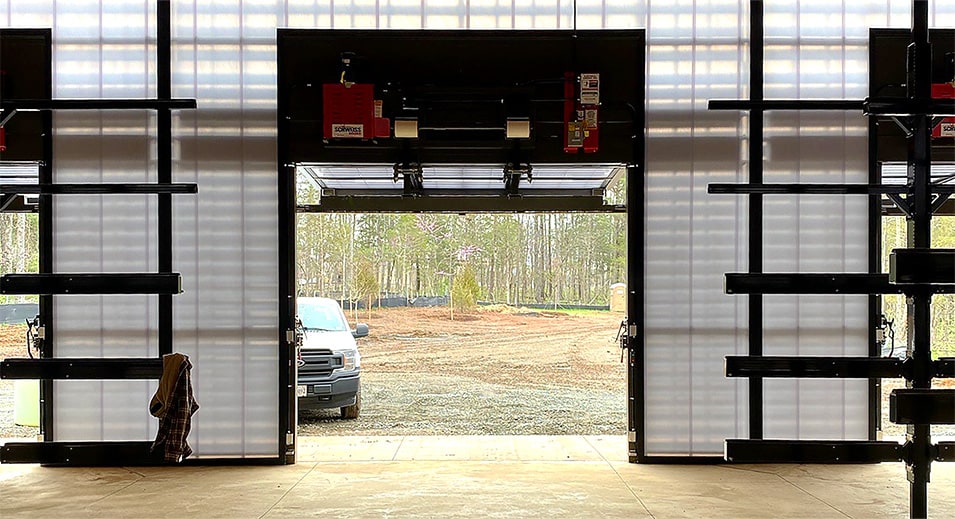 Interior view looking out of opened Schweiss bifold door installed at Beaverdam Reservoir Park to see a car parked outside