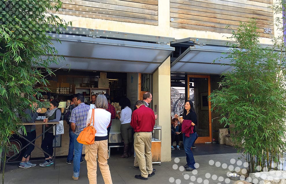 Patrons of Blue Bottle Coffee standing in line underneath Schweiss bifold doors