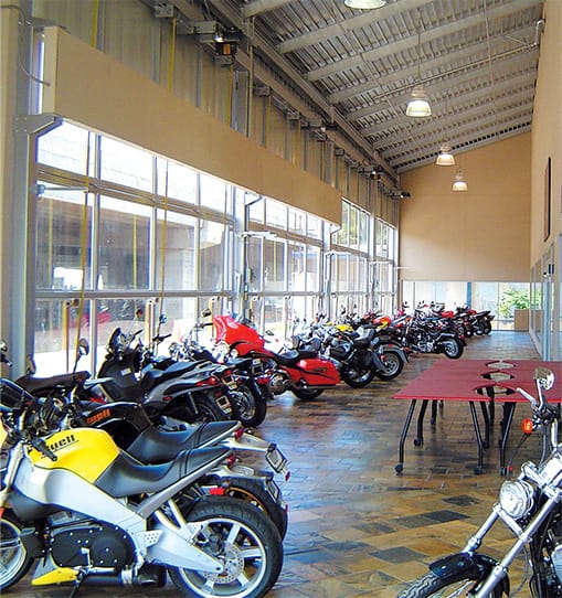 Tons of motorcycles parked inside of Cycle City next to glass bifold doors made by Schweiss Doors