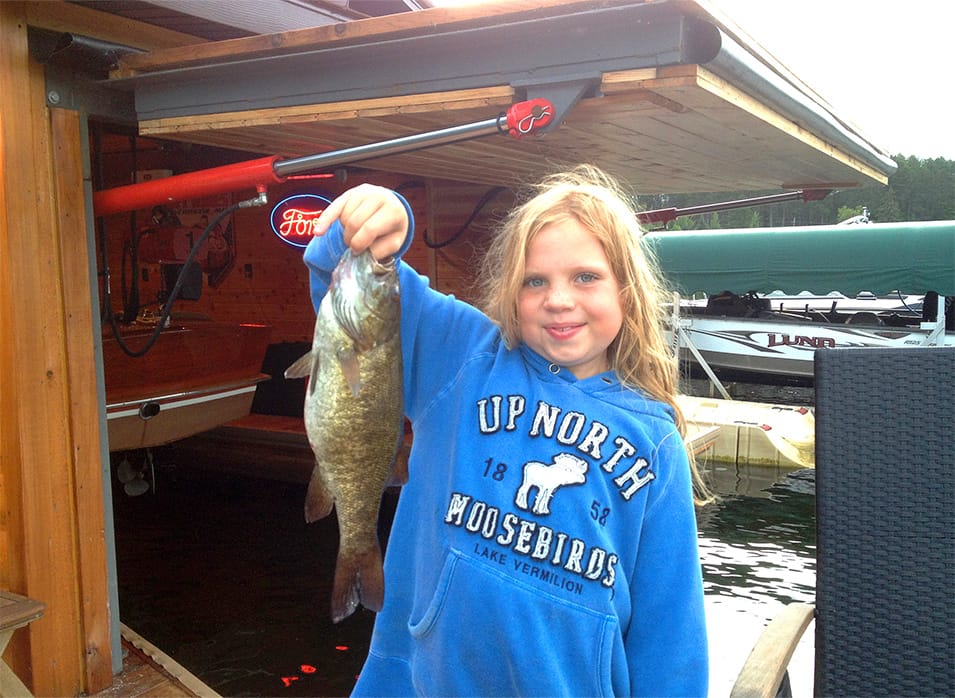 Little girl holding up a fish she caught near the boathouse on Lake Vermilion