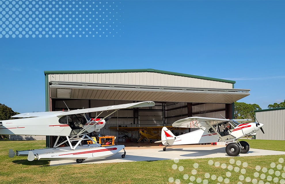 Wide shot of Ray Cook's hangar fitted with a Schweiss bifold door with multiple planes parked inside and outside