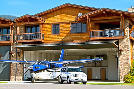An airplane and minivan parked outside hangar fitted with a Schweiss bifold door at Silverwing Airpark