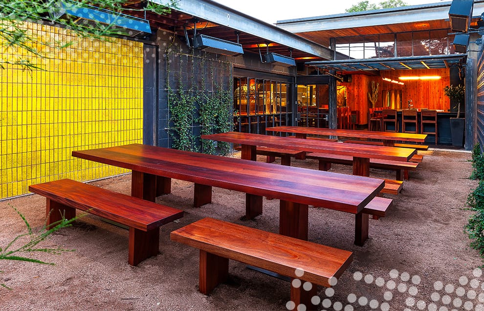 View of communal table area in Sway Restaurant with their custom Schweiss glass hydraulic door fitted in the background