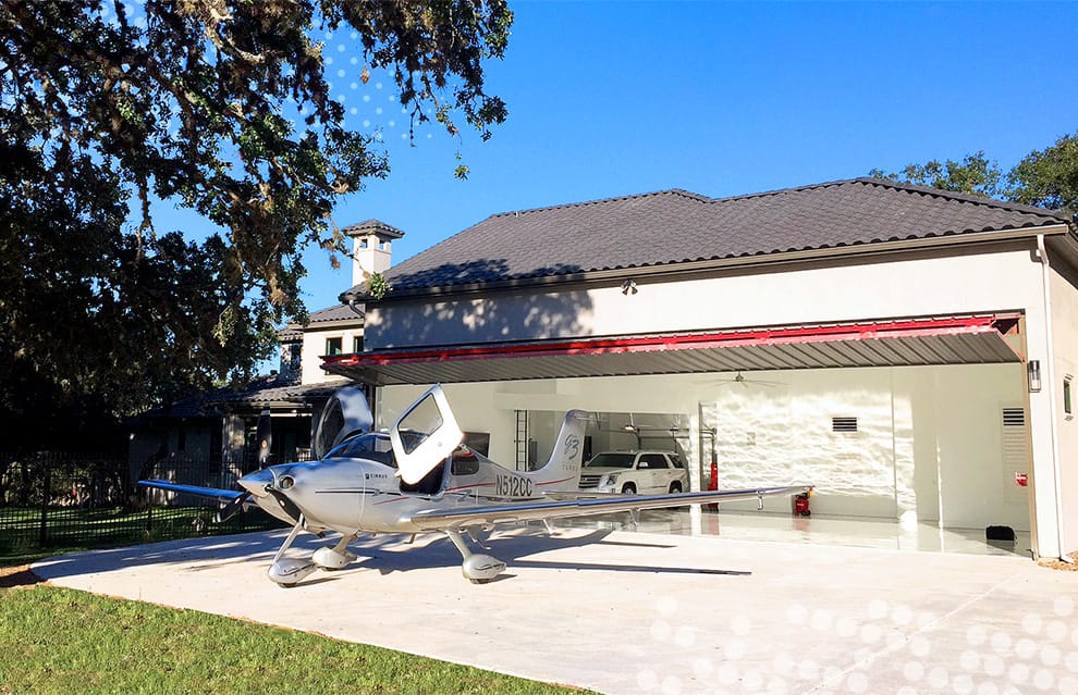 Airplane parked in front of open Schweiss bifoldl door installed on Texas Hangar Home