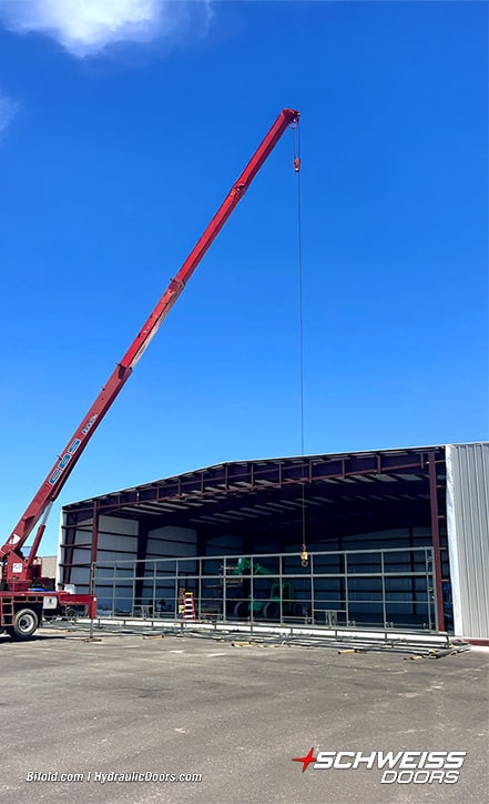 Crane installing 100ft Schweiss bifold frame on a storage hangar