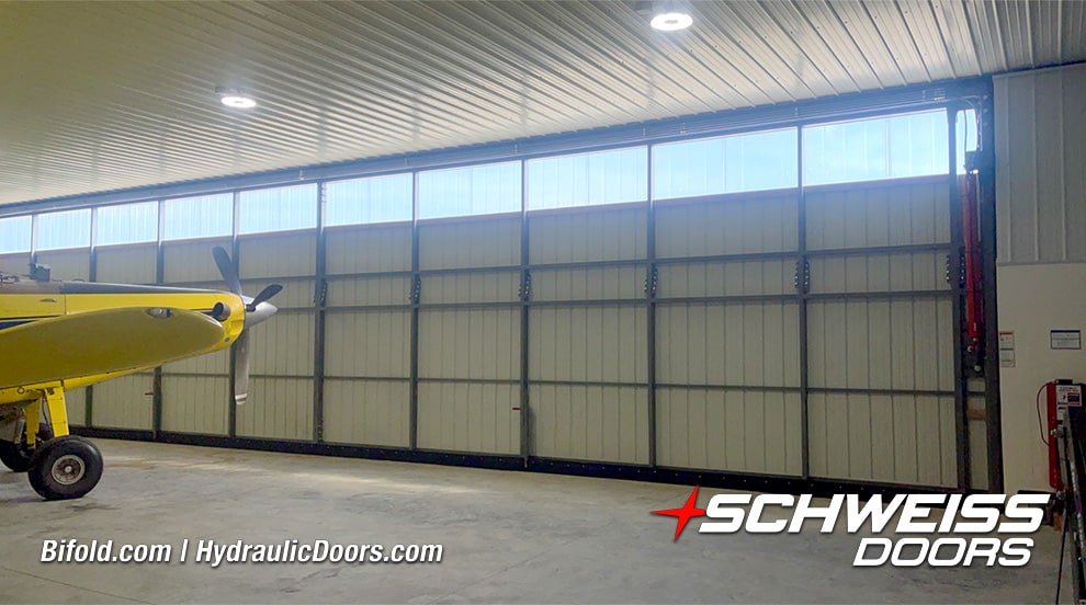 Interior view of closed Schweiss hydraulic door installed on Sam Mast's hangar with plane nearby