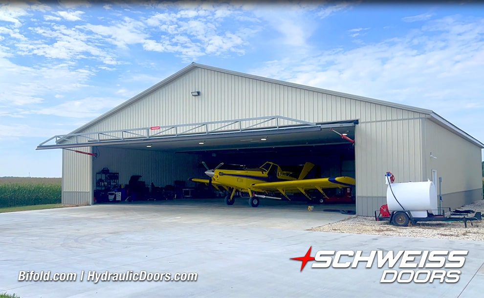 Exterior view of Sam Mast's hangar fitted with a Schweiss hydraulic hangar door shown open with a plane inside
