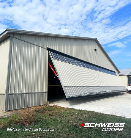 Exterior view of Sam Mast's hangar fitted with a Schweiss hydraulic hangar door shown opening