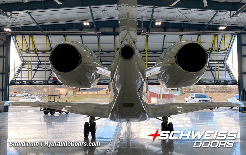 Interior view from behind plane of Schweiss bifold liftstrap hangar door installed on SEI Hangar shown opening