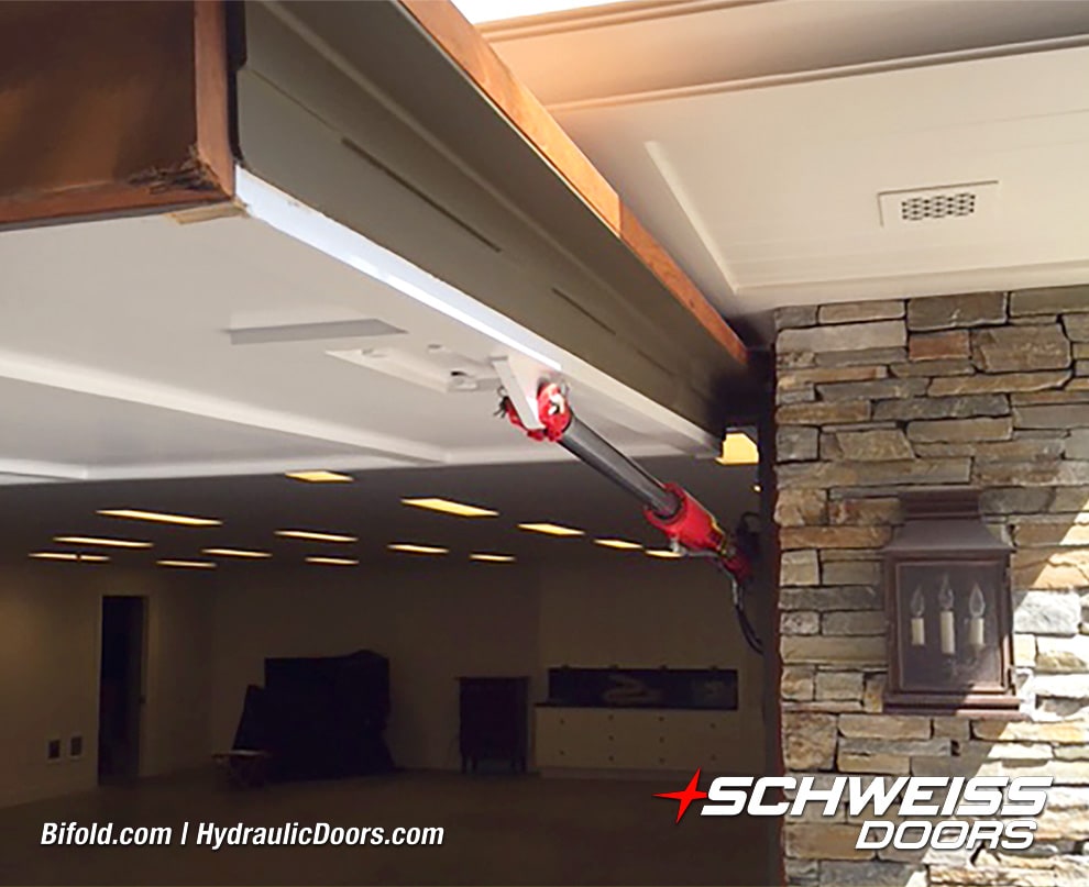 Exterior view of hydraulic cylinders used to operate Schweiss hydraulic door fitted on garage