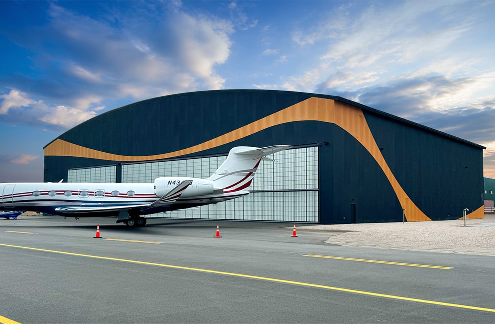 Jet plane parked in front of beautiful and cleanly designed hangar fitted with two large Schweiss hydraulic doors