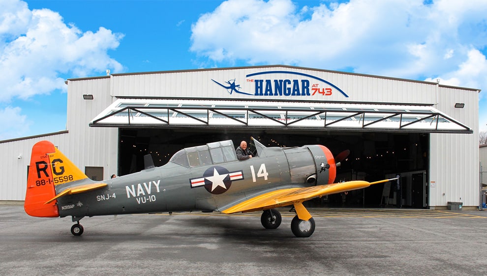 Vintage military planed parked outside of Hangar at 743 in front of Schweiss hydraulic door