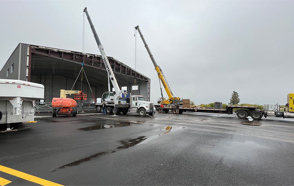 Two cranes installing a Schweiss bifold door onto a hangar