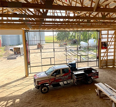 Schweiss installer truck parked near a Schweiss hydraulic door frame installed on a newly constructed building shown closed