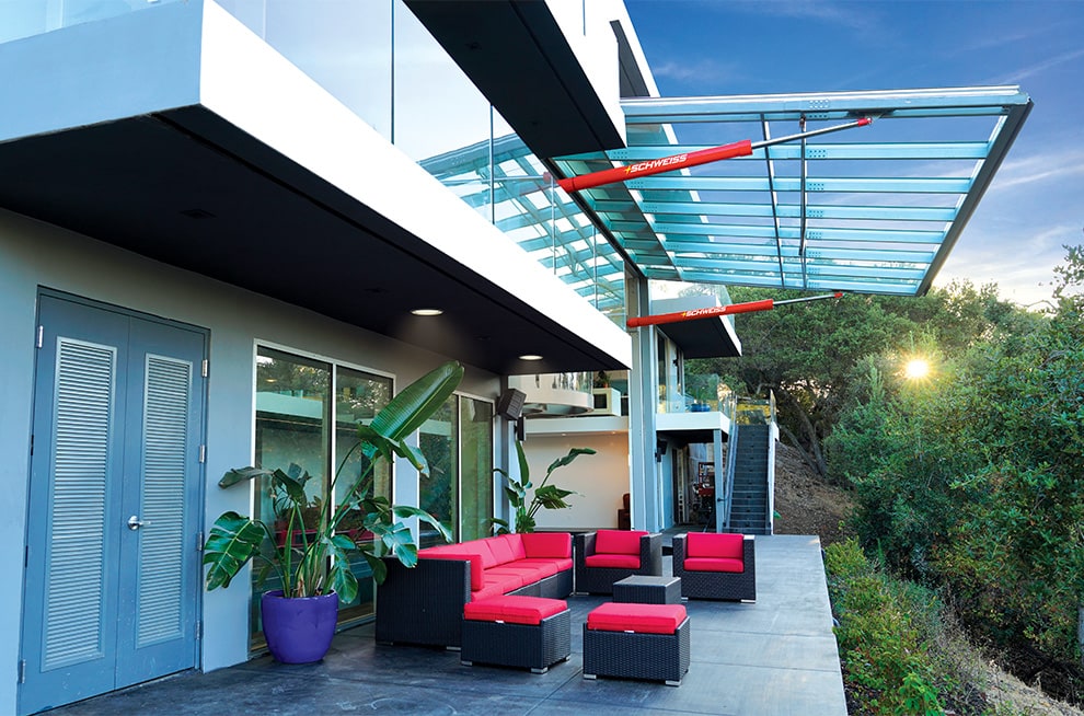 Schweiss hydraulic door made of glass utilized on luxury designer home as a moving wall shown open