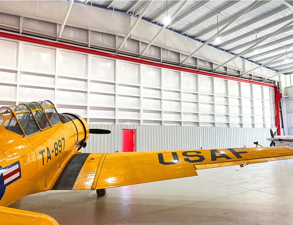 Interior view of vintage military plane parked inside of hangar that is fitted with a Schweiss hydraulic door shown closed