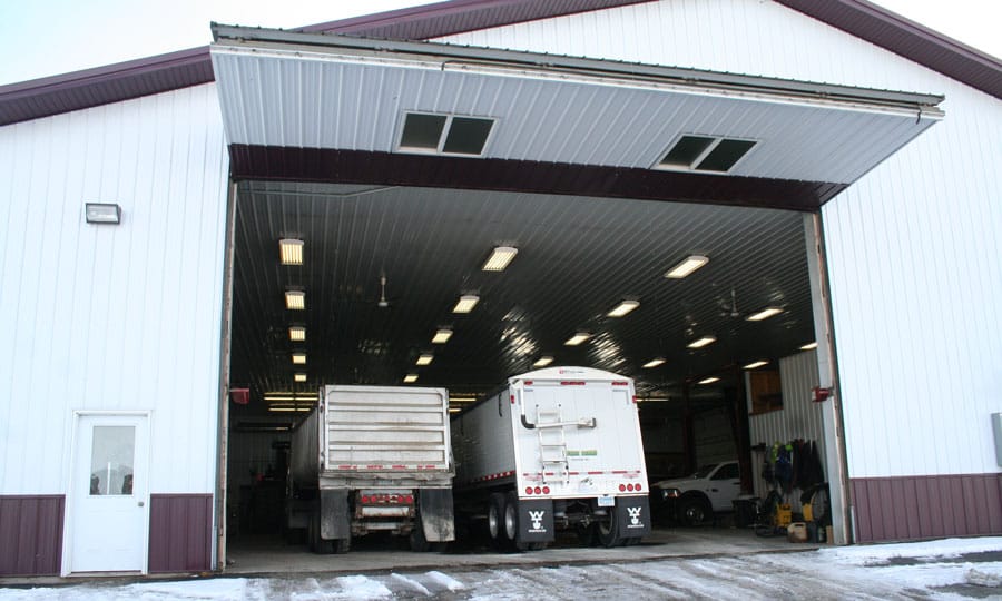 Grain trucks inside shop with bifold farm door