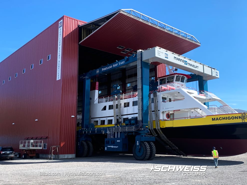 Portland Yacht Service's Door is open for Marine Travelift carrying a large sea vessel.