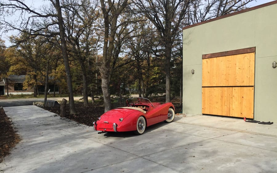 British car by garage next to Wood-clad Bifold Schweiss Door
