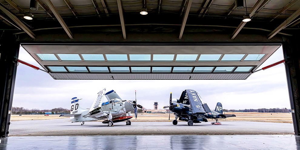 Two planes parked outside of All Steel Schweiss hydraulic door frame installed on hangar
