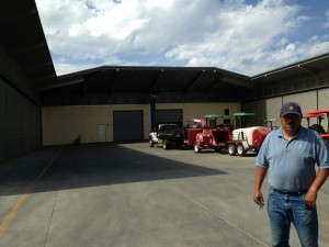 Yuan Martinez standing in front of the winery equipment 