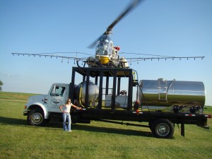 Helicopter's stop to refuel and reload product from a large tanker truck.